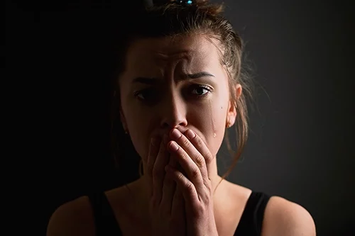 אישה בוכה מסתכלת למצלמה בחושך